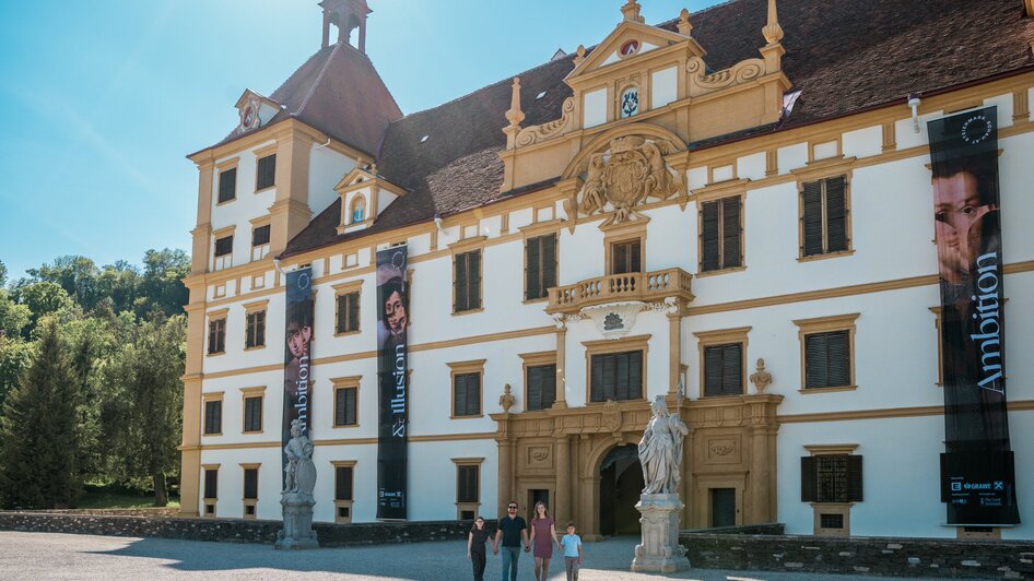 Besucher vor einem kunstvollen Schloss mit großen Bannern. | © Graz Tourismus - Mias Photoart